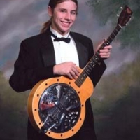 My son, Ian Nathaniel Django Jones, with the dobro banjo I got from Alan Munde. This is his orchestra photo. He was supposed to be holding his violin…